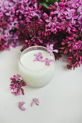 Lilac flowers on the table and in a glass of milk. White background. 