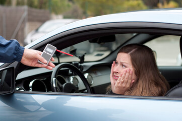 Young female driver arguing with a police officer during test for alcohol content with...