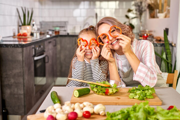 family have fun while cooking in the kitchen, adorable woman with child girl carving fresh vegetables, smile, enjoy the process