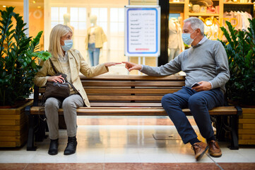 Senior couple trying to hug while maintaining a safety distance during coronavirus times