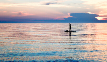 Person paddling paddle board on the lake with a beautiful sunset in the background