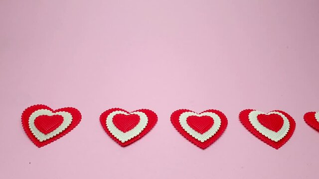 small red hearts on a soft pink colored background, copy space. Valentine's Day concept for design