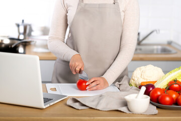 Obraz na płótnie Canvas Woman cooking using the computer to watch virtual culinary class