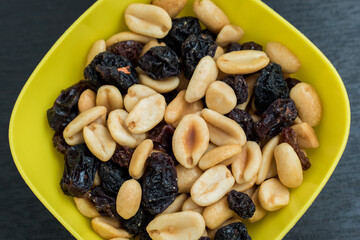 Some peanuts, raisins and nuts in a pot on a dark wooden table 