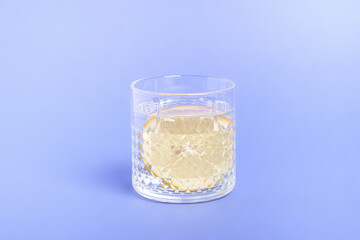 Glass with water and lemon on blue background