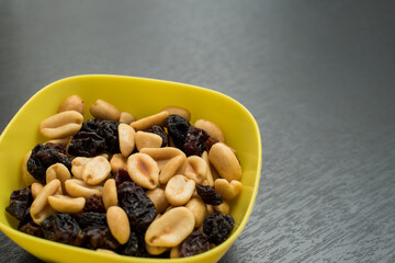Some peanuts, raisins and nuts in a pot on a dark wooden table 