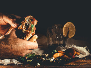 SOME HANDS HOLDING A GOURMET BURGER NEXT TO SOME FRIES