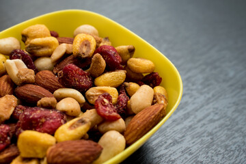 Some peanuts, raisins and nuts in a pot on a dark wooden table 
