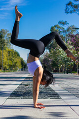 Fototapeta na wymiar brunette and young fitness woman practicing handstand yoga wearing sportswear. wellness, exercise, healthy lifestyle