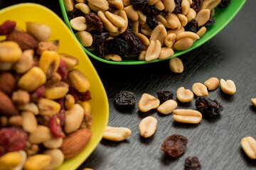 Some peanuts, raisins and nuts in a pot on a dark wooden table 
