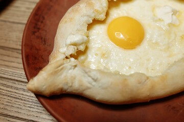 Top view on traditional Adjarian Khachapuri - open baked pie with melted salt cheese suluguni and egg yolk on wooden tray. Traditional georgian food