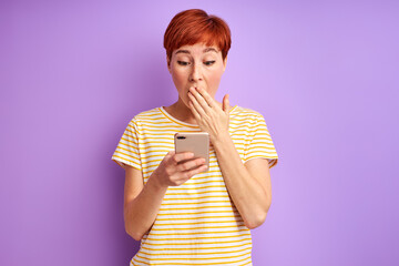 woman in shock by something she saw on mobile phone she is closing her mouth