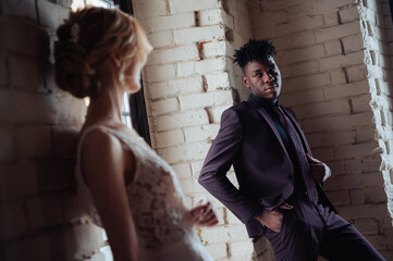 Stylish fashionable afro american groom standing in front of caucasian bride posing.