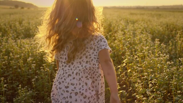 Little Girl Running Across The Field. Sun Over The Horizon. Girl Is Visible Only From The Back.