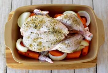 Roasting whole chicken with fresh organic root vegetables ready for cooking healthy family Sunday dinner