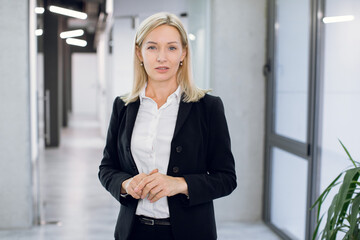 People, business, office concept. Portrait of attractive pleasant confident middle aged businesswoman, financial director, ceo or manager, posing to camera while standing in office hallway interior