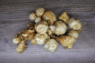 Freshly harvested Jerusalem artichoke crop, fresh nutritious tubers on a wooden board.