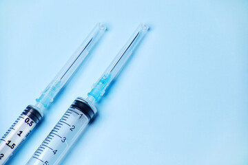 Two medical plastic disposable vaccination syringes with the needle in the cover cap isolated on...