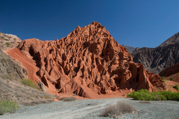 Altiplano. The arid desert and colorful mountains. View of the hiking path across the canyon. The orange sandstone and rocky formation part of Los Colorados in Purmamarca, Jujuy, Argentina. 