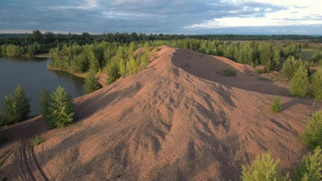 Lake at the site of the extraction of sand and gravel mixture. A mountain of mined gravel.