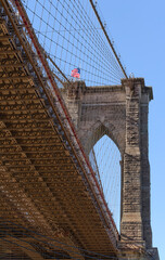 Brooklyn Bridge, New York City, with American Flag on top with underside of bridge.
