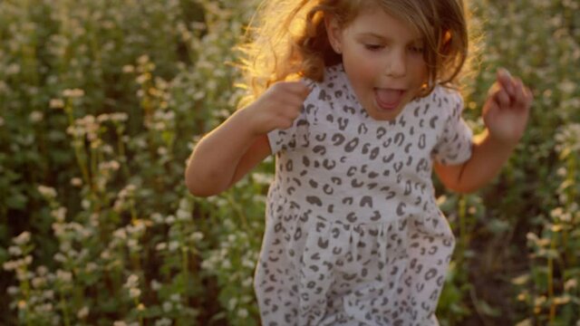 Little Girl Running Across The Field. Pretty Little Girl With Long Curly Hair.