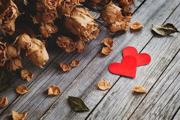 Two red hearts with bouquet of dry roses on wooden background
