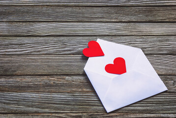 Red paper hearts in envelope on wooden background