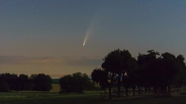 Comet C2020 F3 Neowise moving over rural landscape at morning twilight