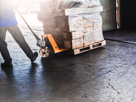 Worker Driving Forklift Loading Shipment Carton Boxes Goods On Wooden Pallet At Loading Dock From Container Truck To Warehouse Cargo Storage In Freight Logistics, Transportation Industrial, Delivery