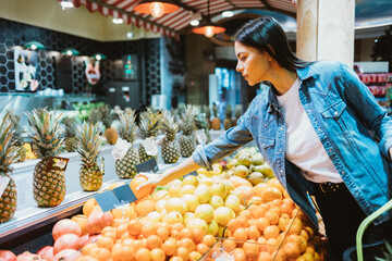 Young woman in denim jacket buys fruits
