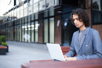 Man works at a laptop outdoors.