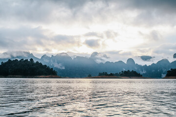 Coastline with cloudy sunset sky, sea and mountains in the Khao Sok National Park, Suratthani Thailand. Nature in twilight period which including of sunrise over the sea. 