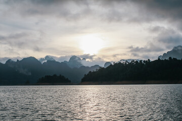 Coastline with cloudy sunset sky, sea and mountains in the Khao Sok National Park, Suratthani Thailand. Nature in twilight period which including of sunrise over the sea. 