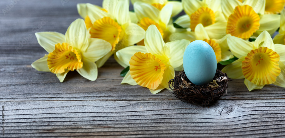 Sticker Select focus of a standing egg in nest with spring daffodil and rustic wood in background