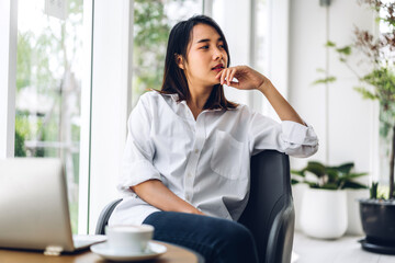 Portrait of smiling happy beautiful asian woman relax using technology of laptop computer sitting on chair.Young hipster asian girl freelancer business thinking with new idea content in cafe 
