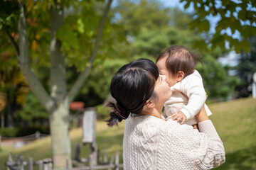 Fototapeta premium 秋の公園で高い高いをするママ 