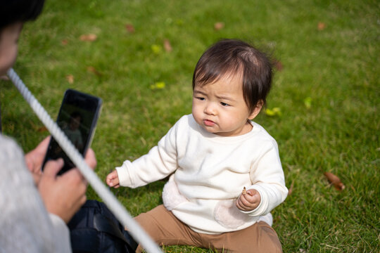 公園で遊ぶ赤ちゃんを撮影するママ（不機嫌）
