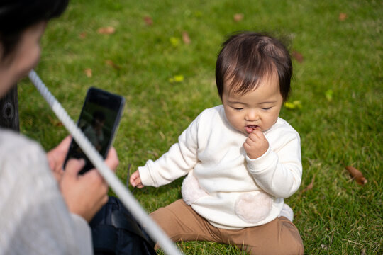 公園で遊ぶ赤ちゃんを撮影するママ（無関心）
