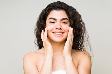 Young woman moisturizing her skin with face cream