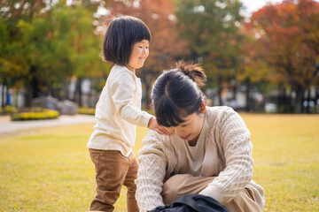 Naklejka na ściany i meble 秋の公園で遊ぶママと子供 