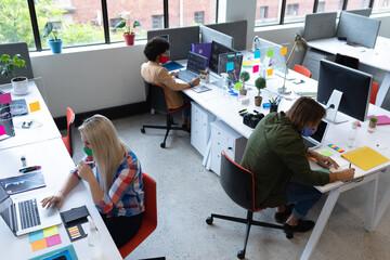 Diverse group of business people wearing face masks in creative office