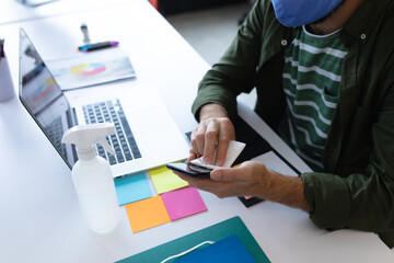 Caucasian businessman wearing face mask in creative office