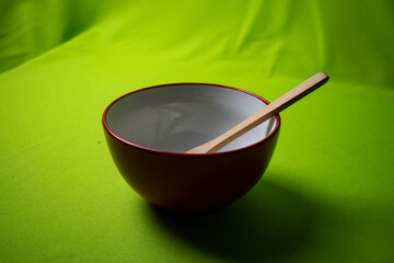 red bowl with wooden spoon with green background