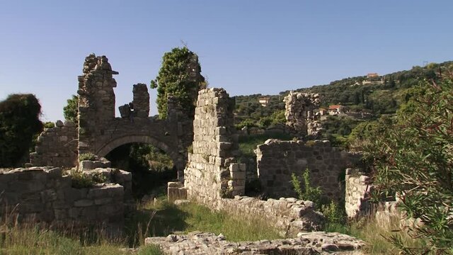 Walls of the old stone fortress with arch and trees on a bright day