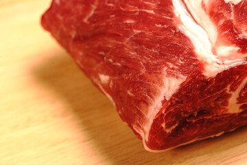 Red meat lies on a wooden board. Visible layers of fat and texture of meat. Pork