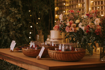 wedding cake decorated with pink flowers on a wooden table with background lights.