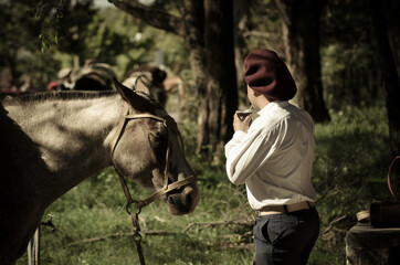 Gaucho tomando mate al lado del caballo