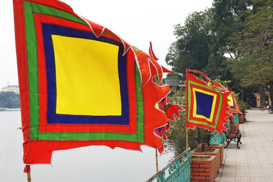 Colorful applique banners blow in the wind along a lake near a Buddhist temple in urban Vietnam