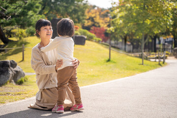秋の公園で遊ぶママと子供
